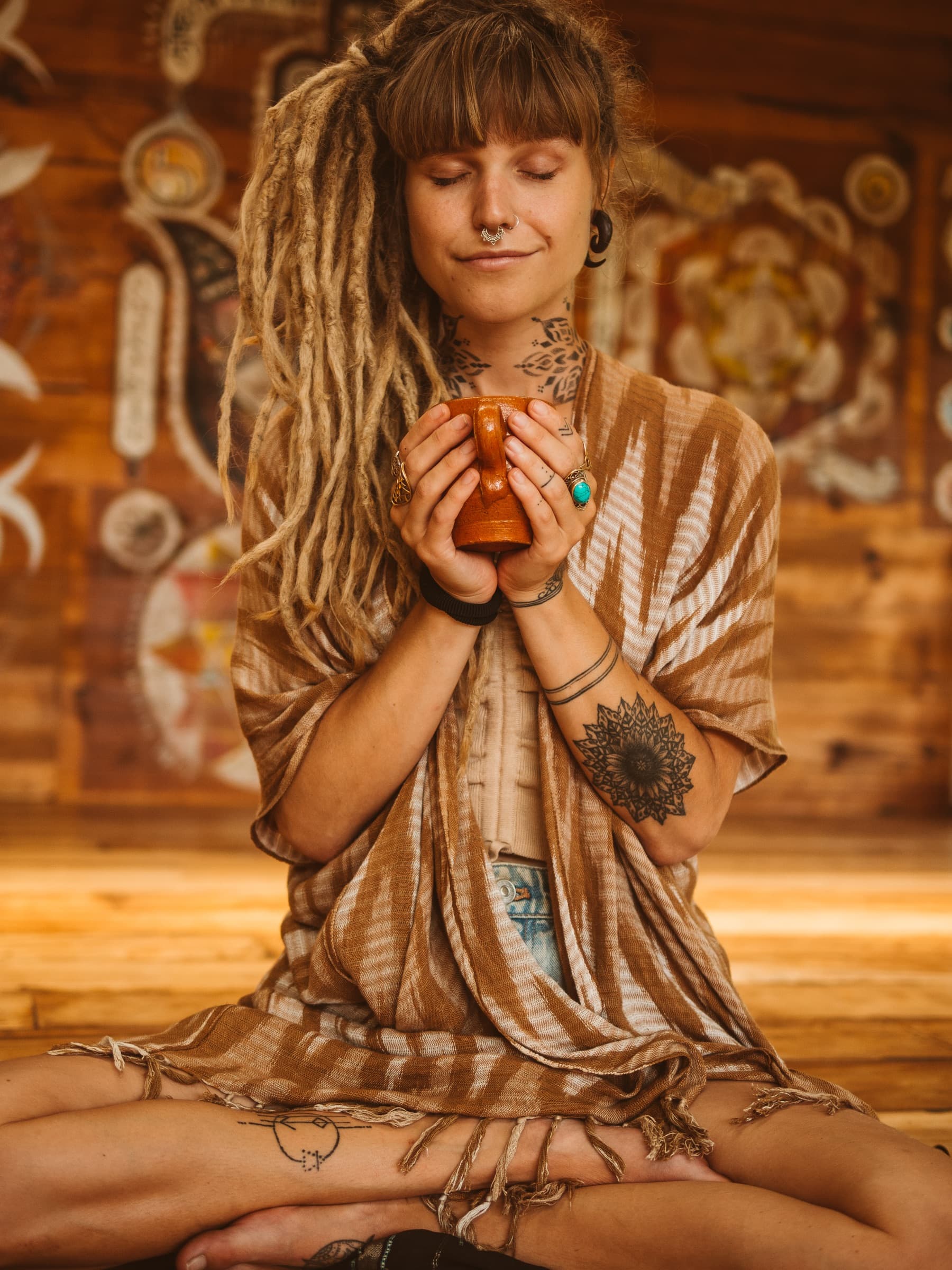 A participant sitting with a mug of ceremonial cacao in the wooden shala