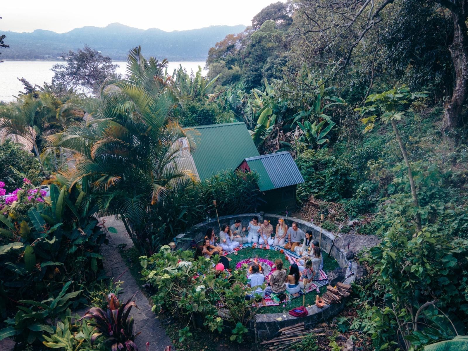 Circle gathered in the garden at Mystical Yoga Farm, lake and volcanoes beyond